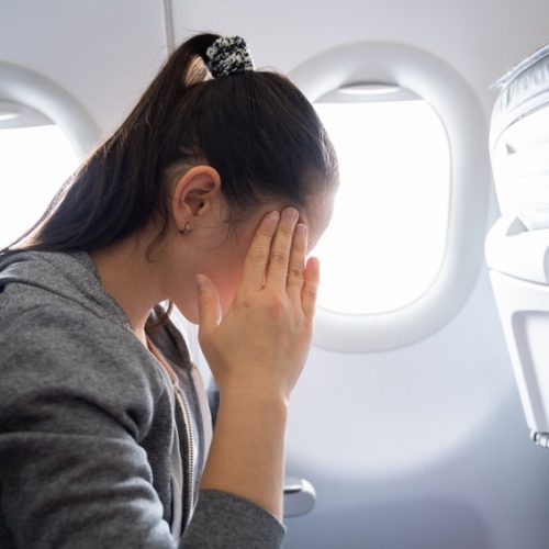 Young Woman Suffering From Airsickness In Airplane